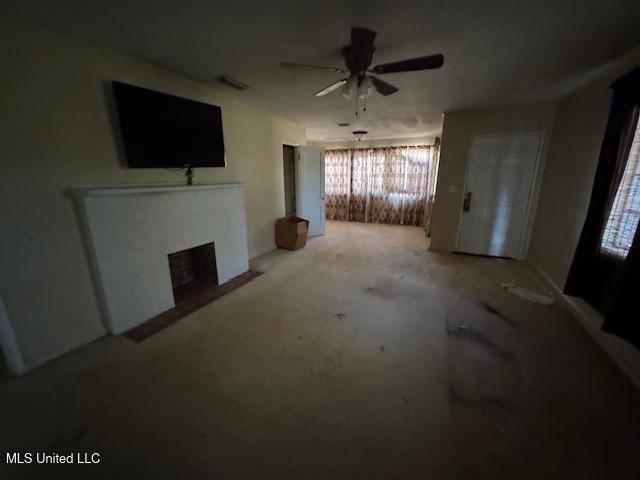 living room featuring a fireplace with flush hearth and a ceiling fan