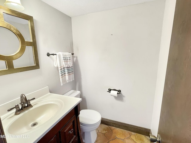 bathroom featuring vanity, a textured ceiling, and toilet