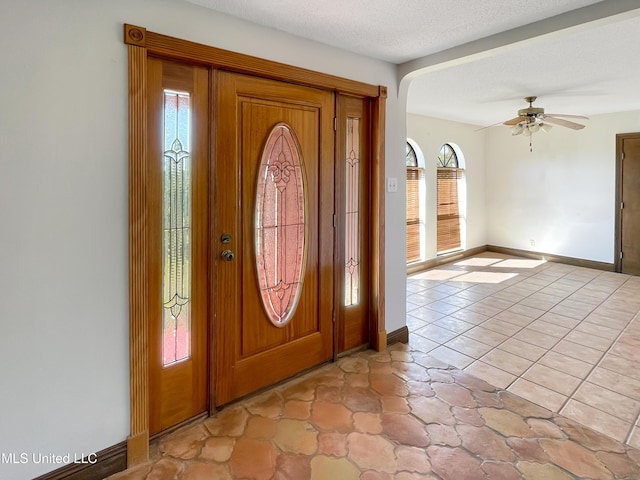 tiled foyer featuring a textured ceiling, ceiling fan, and a healthy amount of sunlight