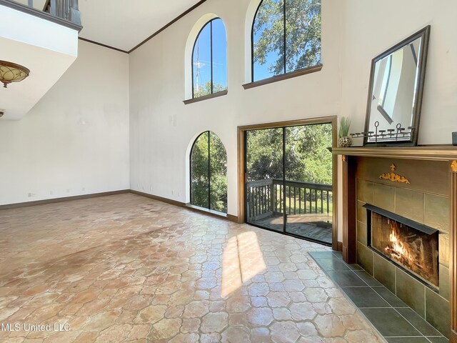 unfurnished living room with a towering ceiling, a fireplace, and a wealth of natural light