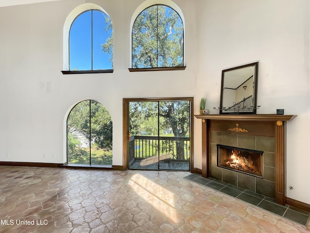 unfurnished living room featuring a towering ceiling and a fireplace