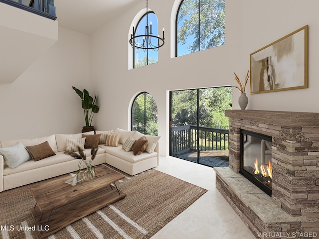 living room with a stone fireplace, a towering ceiling, and a chandelier