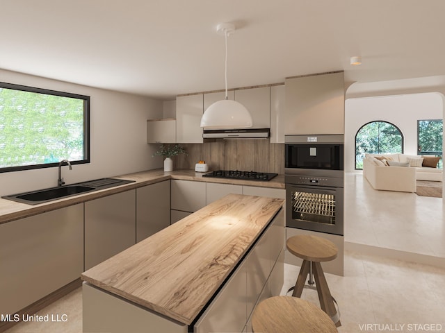 kitchen with a center island, backsplash, black gas stovetop, sink, and decorative light fixtures