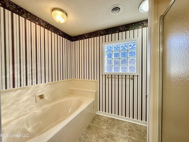 bathroom featuring plus walk in shower and a textured ceiling