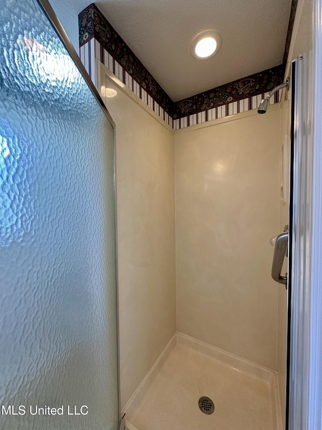 bathroom featuring a shower with shower door and a textured ceiling