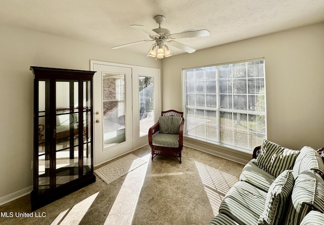 living area with a textured ceiling and ceiling fan