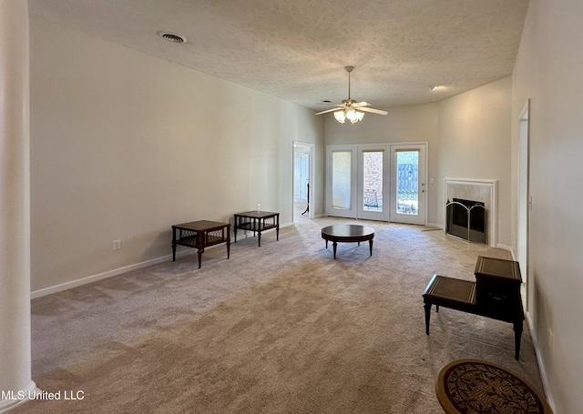 living room featuring a textured ceiling, ceiling fan, and light colored carpet