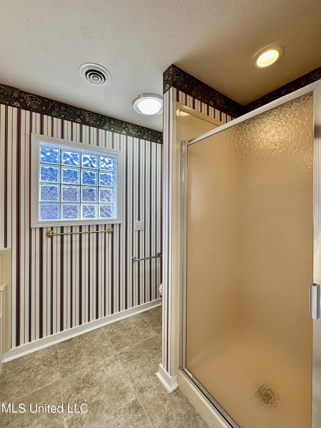 bathroom with a textured ceiling, toilet, and a shower with door