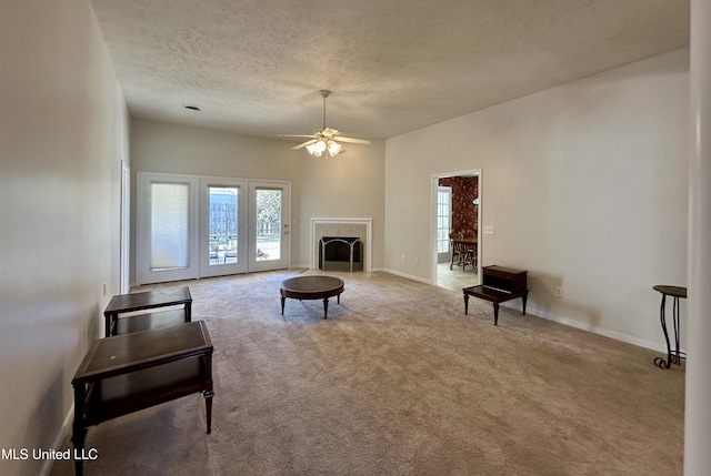 carpeted living room featuring ceiling fan, a textured ceiling, and a fireplace