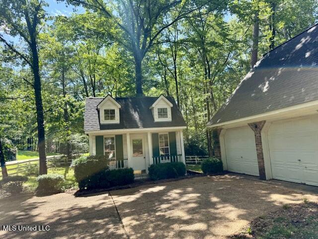 618 Gordon Pl Unit 618, Madison, MS 39110 - cape cod-style house with covered porch, a garage, driveway, and view of scattered trees