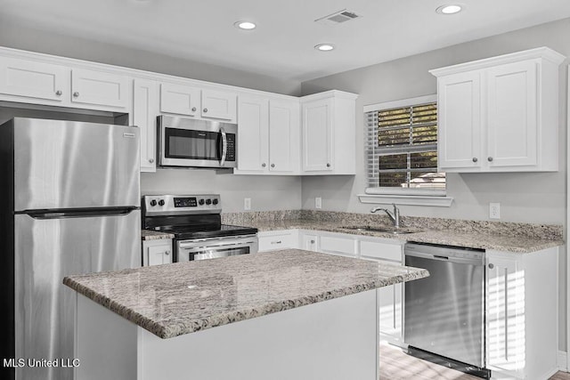 kitchen with white cabinetry, sink, a center island, stainless steel appliances, and light stone counters