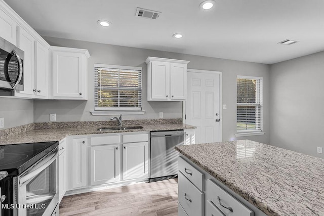 kitchen featuring sink, stainless steel appliances, light stone counters, light hardwood / wood-style floors, and white cabinets