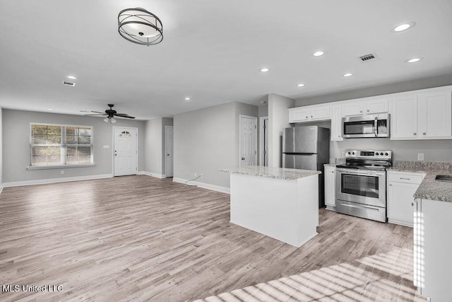 kitchen with ceiling fan, white cabinetry, light hardwood / wood-style floors, a kitchen island, and appliances with stainless steel finishes