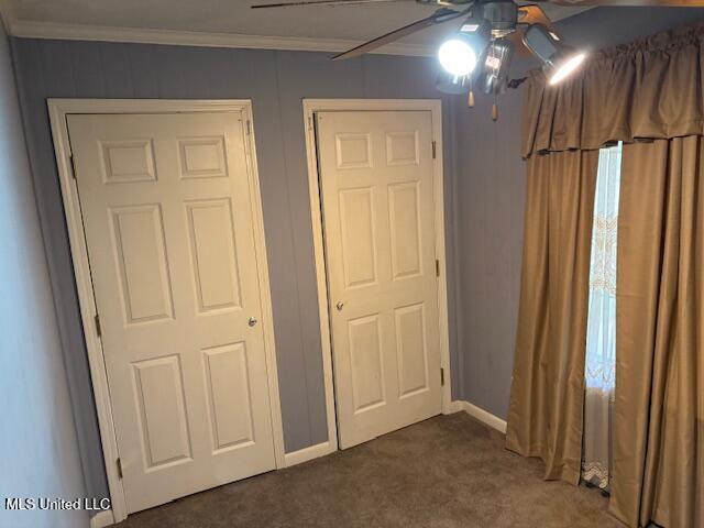 unfurnished bedroom with baseboards, ornamental molding, and dark carpet