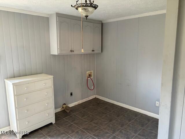 laundry room with dark tile patterned flooring, a textured ceiling, cabinet space, crown molding, and hookup for a washing machine