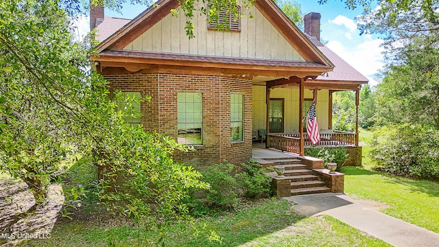 2548 Furrs Mill Dr, Wesson, MS 39191 - view of front of home with a chimney, covered porch, brick siding, board and batten siding, and a front yard