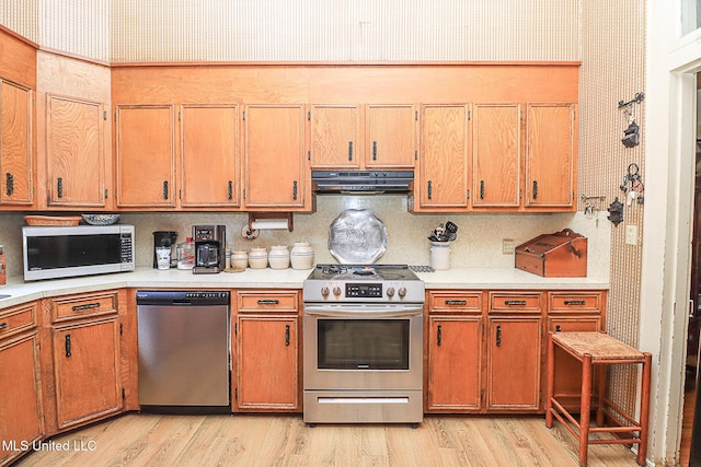 2548 Furrs Mill Dr, Wesson, MS 39191 - kitchen featuring stainless steel appliances, under cabinet range hood, wallpapered walls, light wood-style flooring, and light countertops