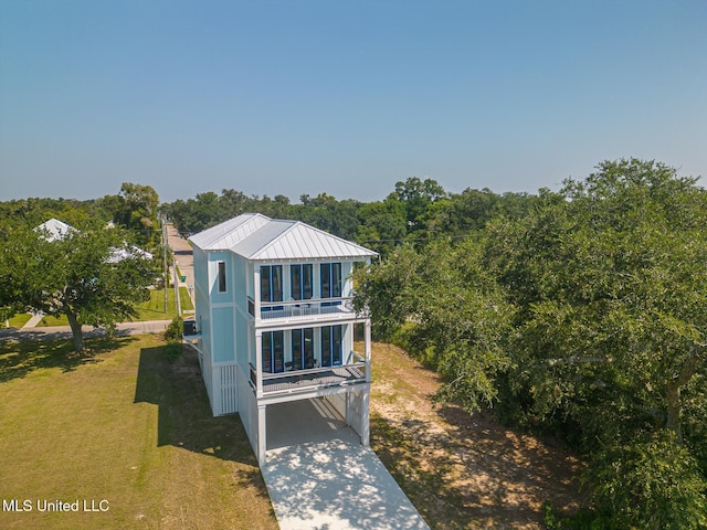 view of front of home with a carport, a balcony, and a front yard