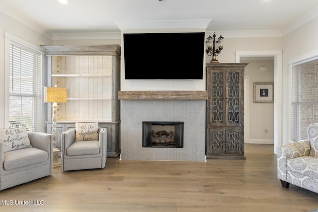 living room with hardwood / wood-style flooring, crown molding, and a tiled fireplace