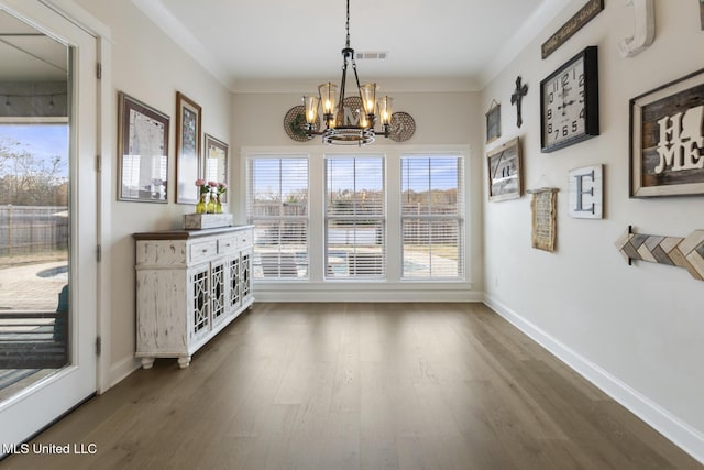 unfurnished dining area with crown molding, dark wood-type flooring, and an inviting chandelier