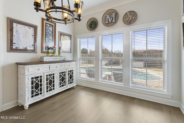 unfurnished dining area featuring plenty of natural light, dark hardwood / wood-style flooring, crown molding, and an inviting chandelier