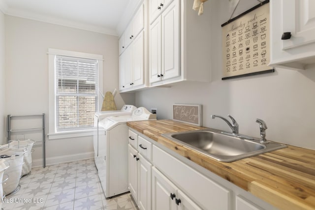 clothes washing area featuring crown molding, cabinets, independent washer and dryer, and sink