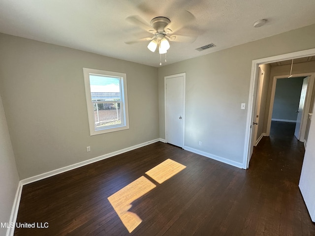 unfurnished bedroom featuring ceiling fan, dark hardwood / wood-style flooring, a textured ceiling, and a closet