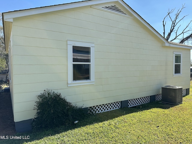 view of side of home with a yard and central AC