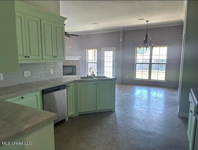 kitchen featuring a wealth of natural light, stainless steel dishwasher, a peninsula, and finished concrete flooring