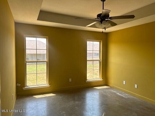 spare room with a wealth of natural light, concrete floors, and baseboards