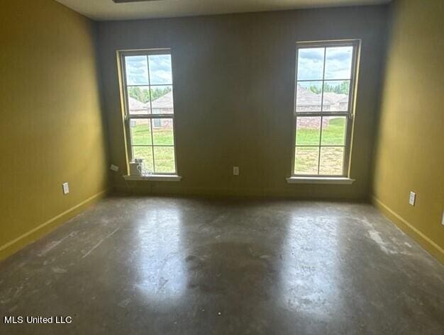 unfurnished room featuring baseboards and unfinished concrete floors