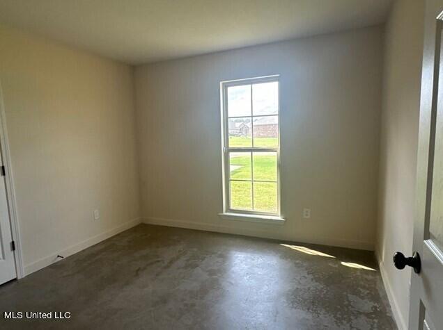 spare room with baseboards and concrete flooring
