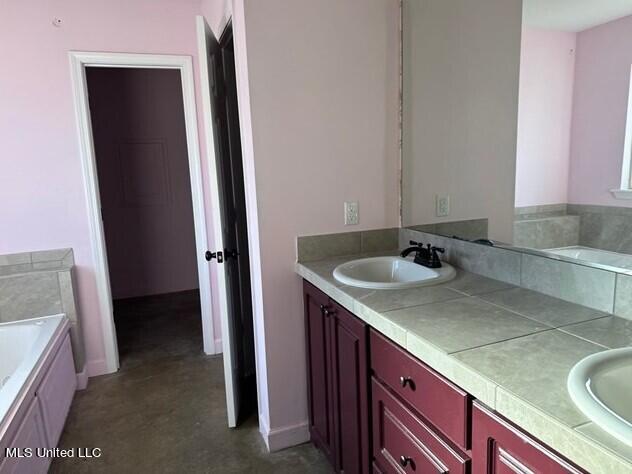 full bathroom with a garden tub, double vanity, and a sink