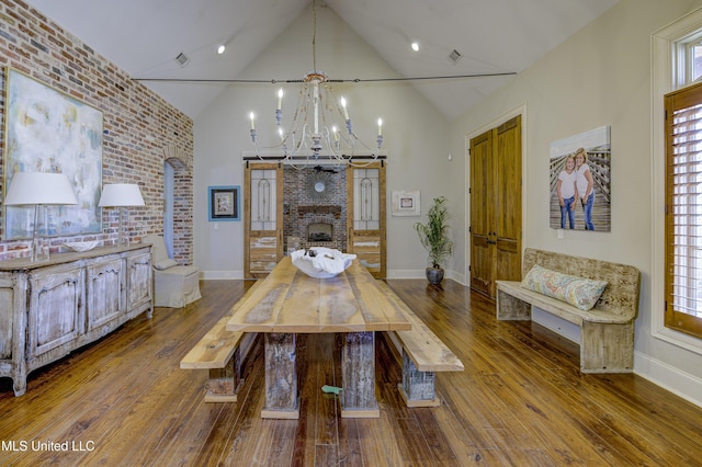 dining area featuring brick wall, lofted ceiling, a chandelier, and light hardwood / wood-style flooring