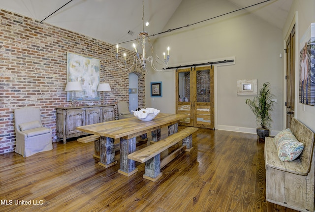 dining area with brick wall, a barn door, high vaulted ceiling, and wood-type flooring