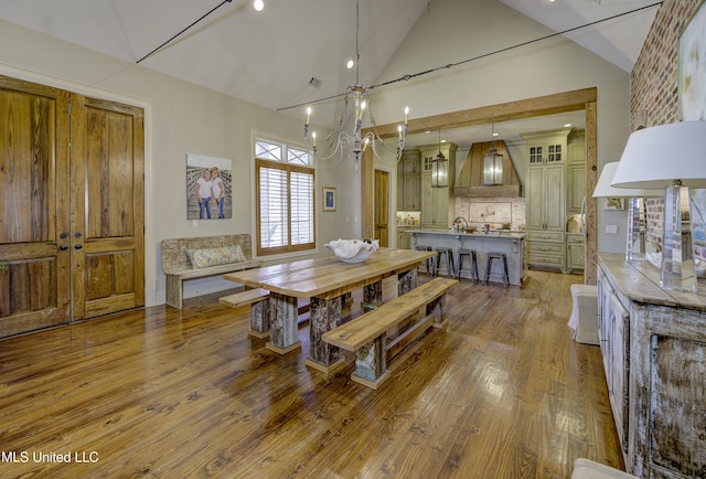 dining area with high vaulted ceiling and light hardwood / wood-style flooring