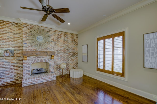 unfurnished living room featuring hardwood / wood-style flooring, brick wall, ornamental molding, and a brick fireplace