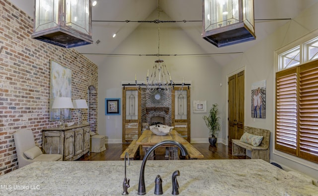 dining area featuring dark hardwood / wood-style flooring, high vaulted ceiling, a barn door, and brick wall