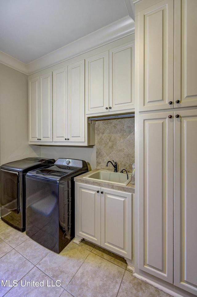 laundry area featuring light tile patterned flooring, separate washer and dryer, sink, cabinets, and crown molding