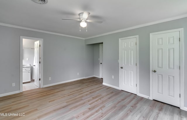 5887 Scotland Rd, Bentonia, MS 39040 - unfurnished bedroom featuring crown molding, light wood-style flooring, two closets, baseboards, and connected bathroom