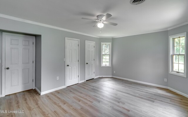 5887 Scotland Rd, Bentonia, MS 39040 - unfurnished bedroom with multiple windows, ornamental molding, light wood-style flooring, baseboards, and multiple closets