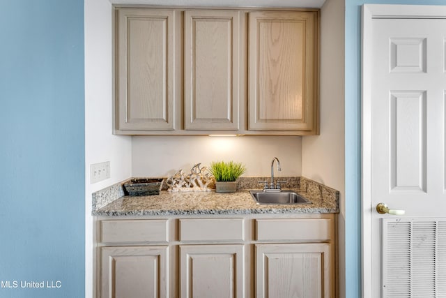 interior space featuring light brown cabinets, light stone counters, and sink