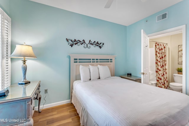 bedroom with connected bathroom, ceiling fan, multiple windows, and light wood-type flooring