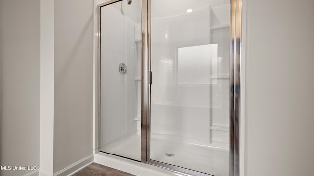 bathroom featuring a shower with door and wood-type flooring