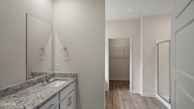 bathroom with hardwood / wood-style flooring, vanity, and walk in shower