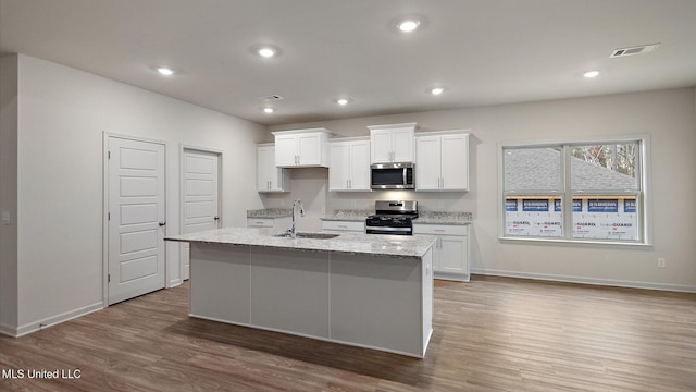 kitchen featuring a kitchen island with sink, sink, white cabinets, and appliances with stainless steel finishes