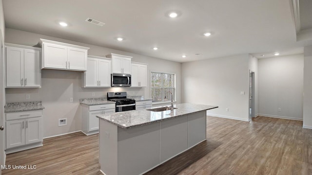 kitchen featuring white cabinetry, appliances with stainless steel finishes, and an island with sink