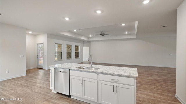 kitchen featuring white cabinetry, sink, stainless steel dishwasher, a tray ceiling, and a center island with sink