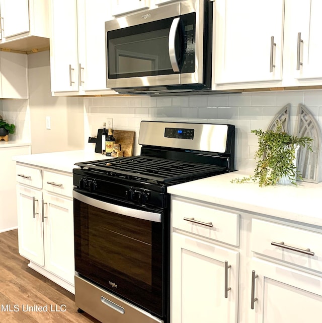 kitchen with white cabinetry, appliances with stainless steel finishes, and hardwood / wood-style floors