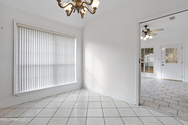 spare room featuring ceiling fan with notable chandelier, vaulted ceiling, and light tile patterned floors